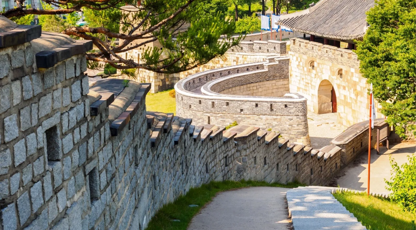 Stone rampart path climbing to the round Seonodae crossbow tower at Hwaseong Fortress