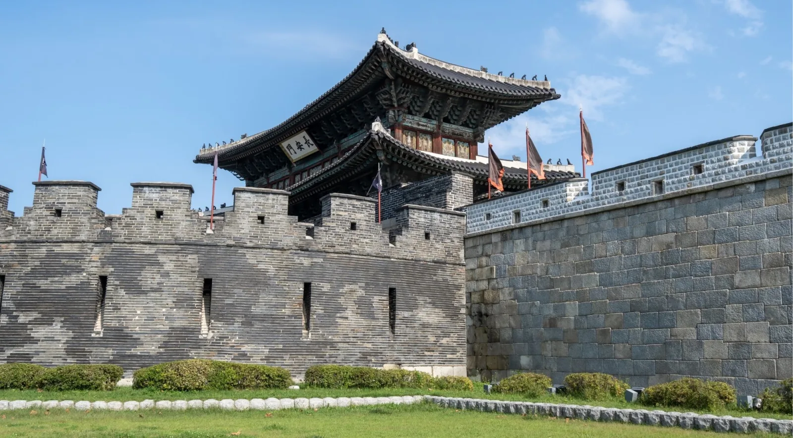 Two-storey gate pavilion rising above the grey stone wall of Suwon Hwaseong