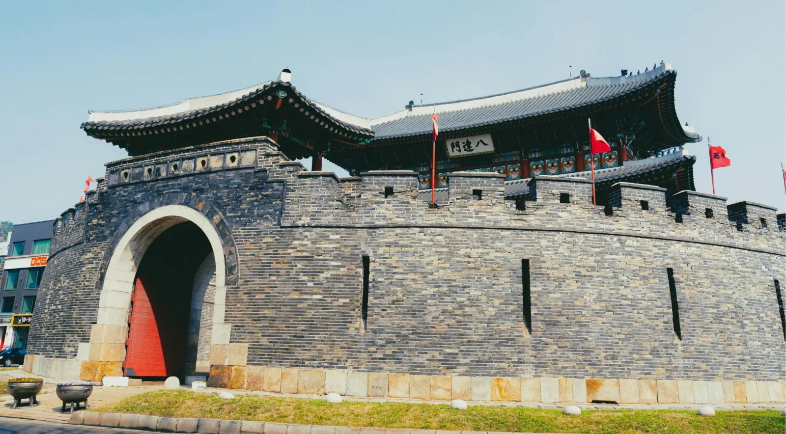 Hwaseomun gate and its curved barbican wall with flags flying at Hwaseong Fortress