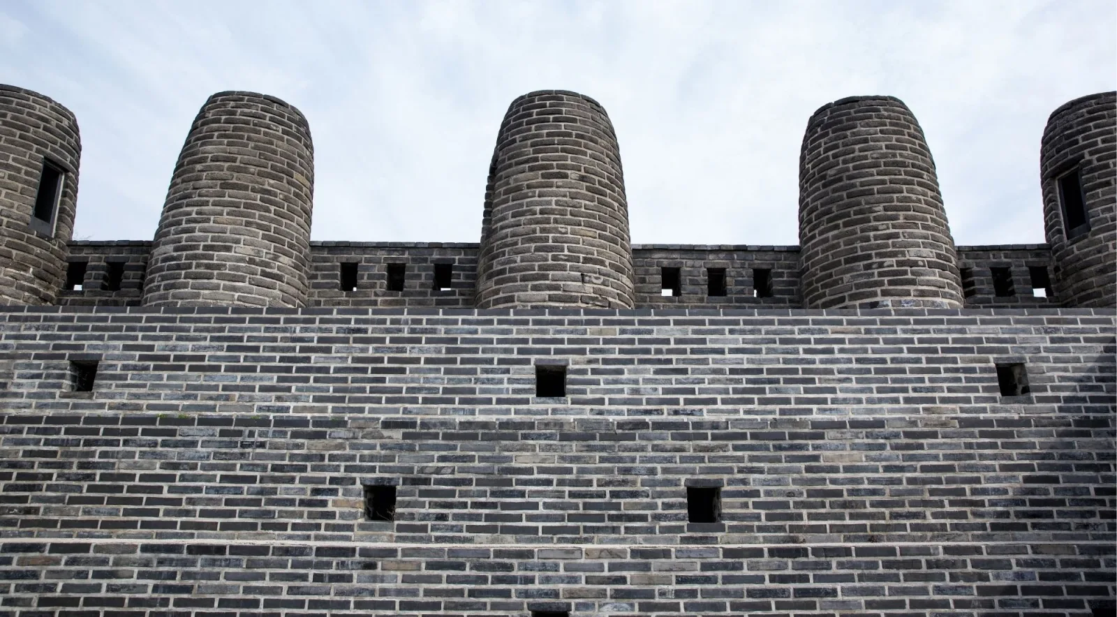 Rounded merlons and gun ports along the crenellated parapet of the Hwaseong wall