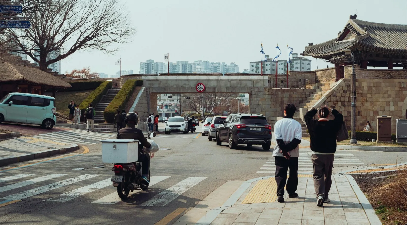 Pedestrians and traffic passing the Hwaseong Fortress wall in central Suwon