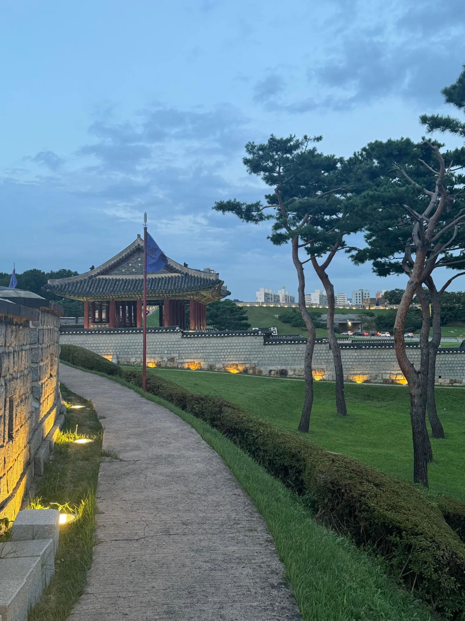 Lit path and pavilion along the Hwaseong Fortress wall in the evening