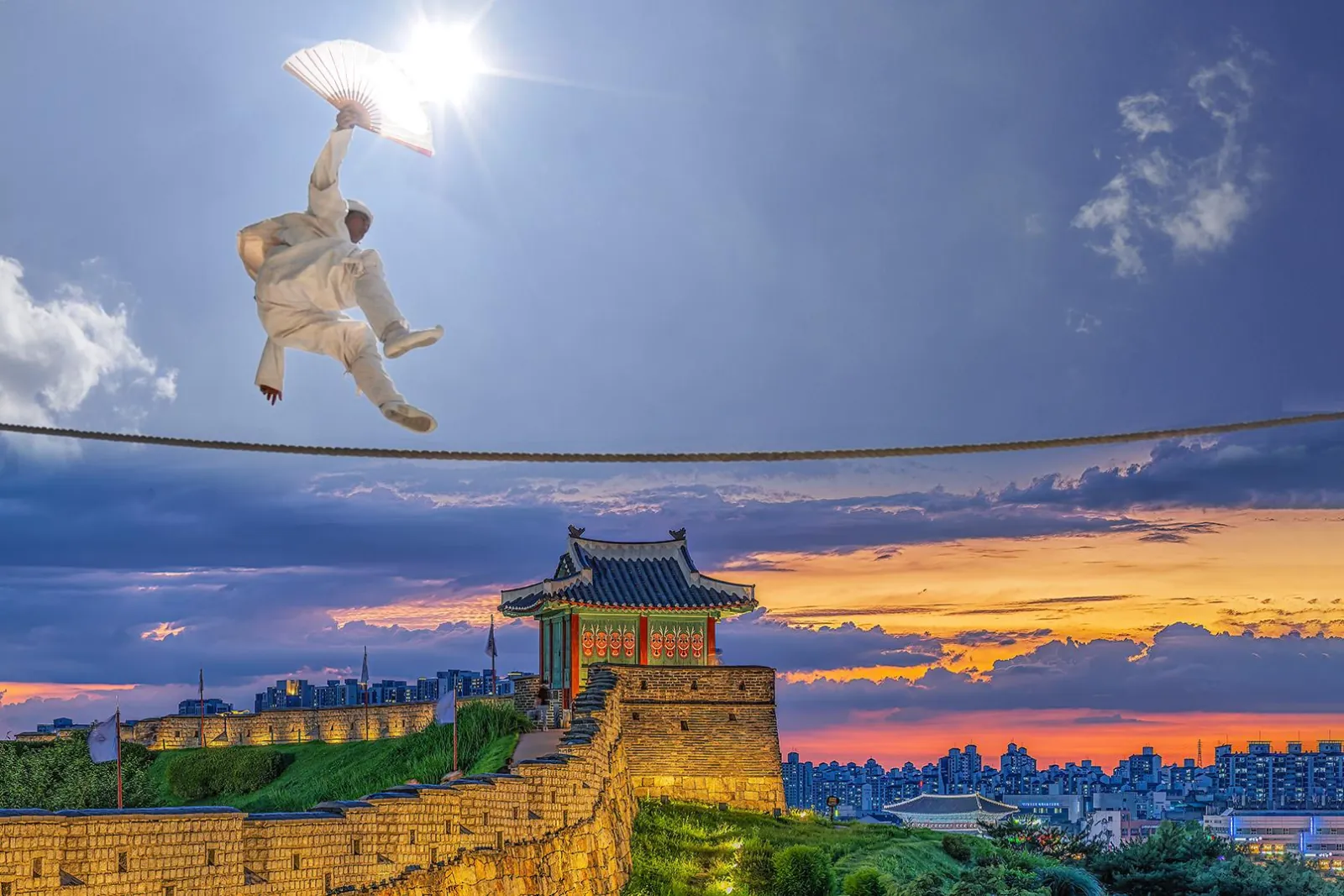 Tightrope walker silhouetted above Suwon Hwaseong Fortress at sunset