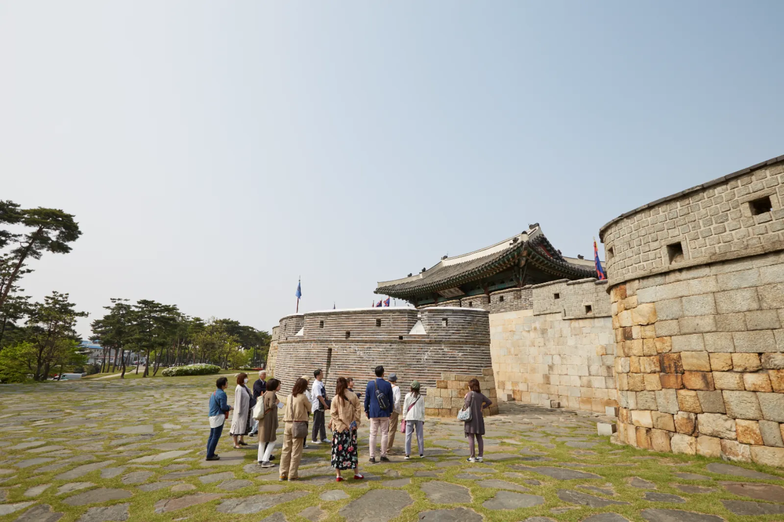 Tour group beside the round brick Seobuk Gongsimdon watchtower on the Hwaseong wall