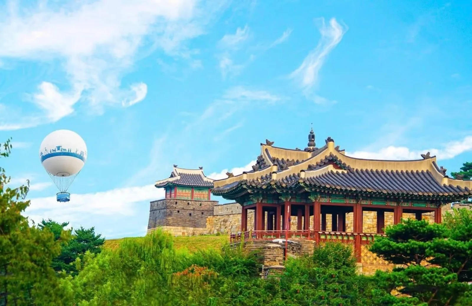 The Flying Suwon balloon rising beside a Hwaseong Fortress pavilion