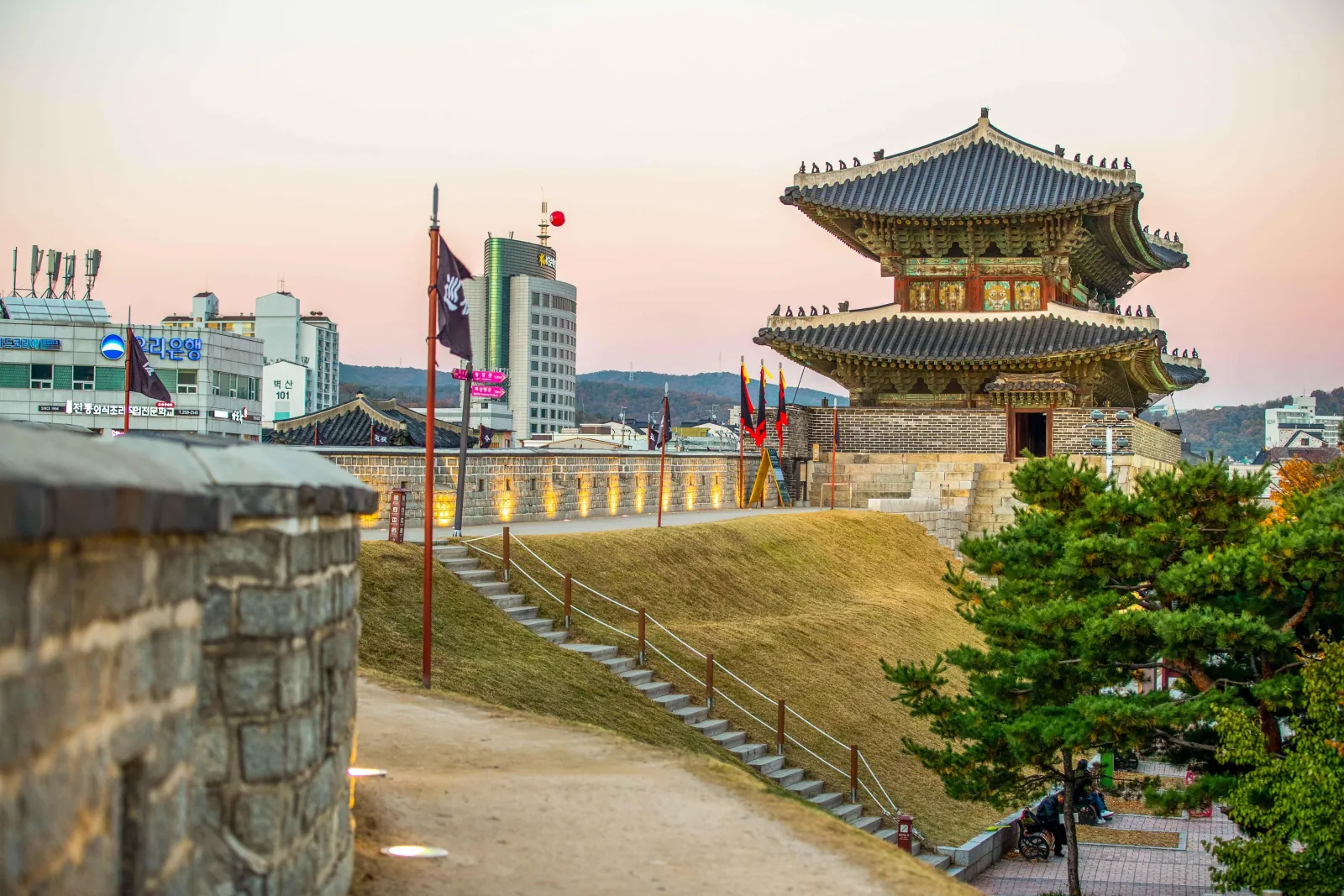 Hwaseong Fortress gate and flags seen from the rampart path